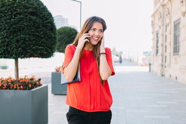 Gelukkige vrouw die op smartphone in stad spreekt