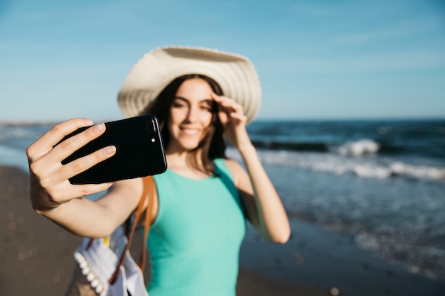 Gelukkige vrouw die selfie bij het strand nemen