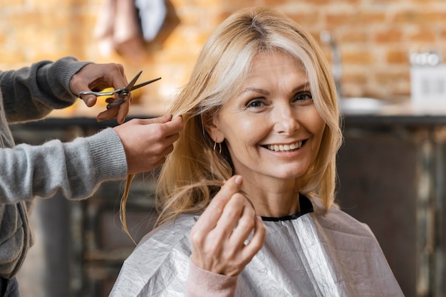 Gelukkige vrouw die thuis een kapsel krijgt met kapper