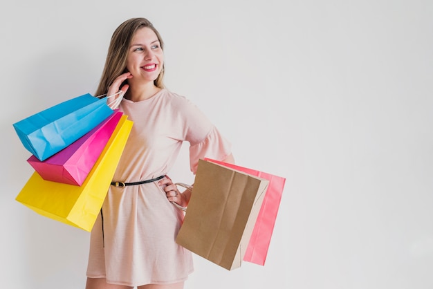 Gelukkige vrouw die zich met heldere het winkelen zakken bevindt