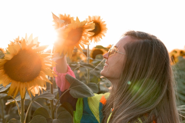 Gelukkige vrouw die zonnebloem bekijkt