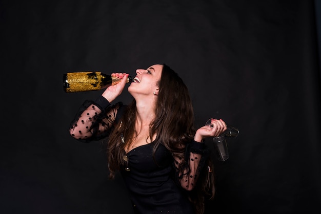 Gratis foto gelukkige vrouw het drinken champagne van fles