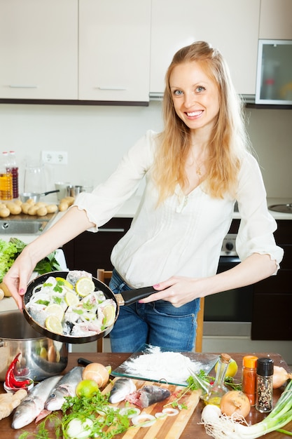 Gratis foto gelukkige vrouw koken vis met citroen