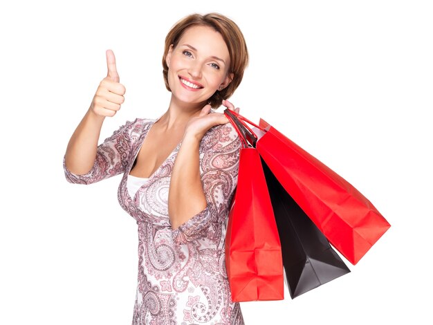 Gelukkige vrouw met boodschappentassen na het winkelen met duimen omhoog gebaar