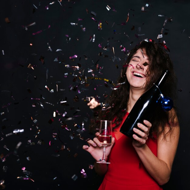 Gratis foto gelukkige vrouw met champagnefles en glas