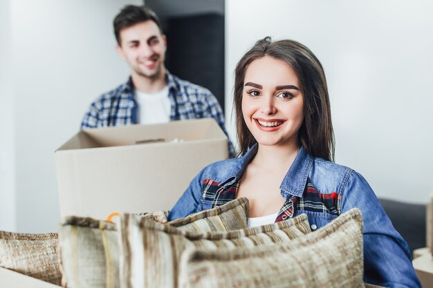 Gelukkige vrouw met doos op handen in nieuw huis