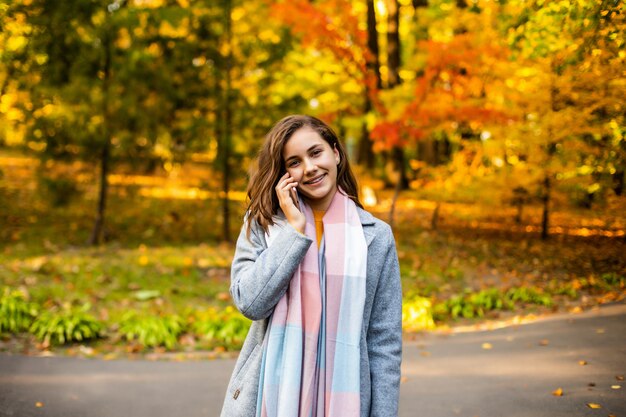 Gelukkige vrouw op mobiele telefoon in herfst park