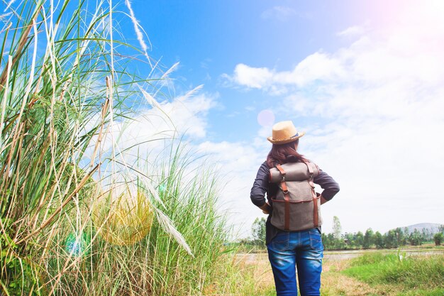 Gelukkige vrouw reiziger op zoek naar blauwe lucht met veld van gras, wanderlust reis concept, ruimte voor tekst