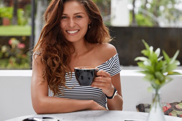 Gelukkige vrouw zittend op een koffieshop