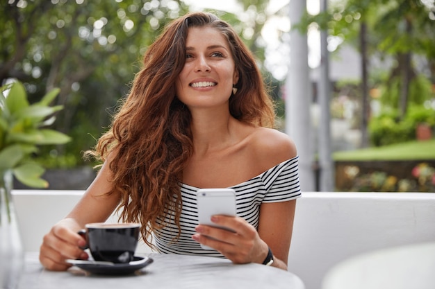 Gelukkige vrouw zittend op een koffieshop