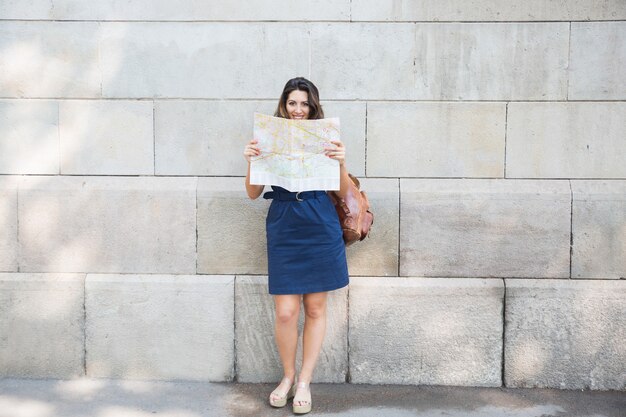 Gelukkige vrouwelijke reiziger raadplegen kaart in de straat