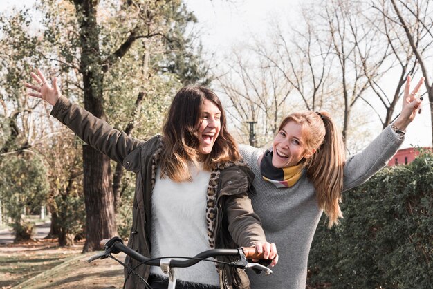 Gelukkige vrouwen die fiets in park berijden