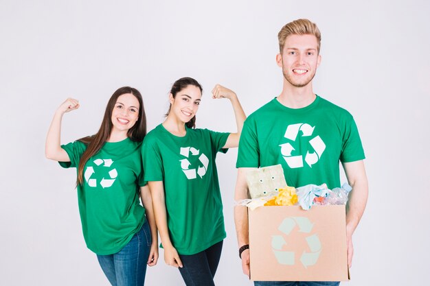 Gelukkige vrouwen die hun spieren achter de recyclebare puntenkartondoos van de mensenholding buigen