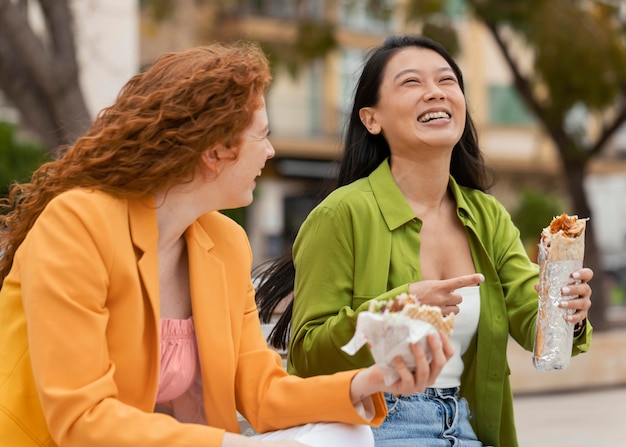 Gelukkige vrouwen die samen straatvoedsel eten