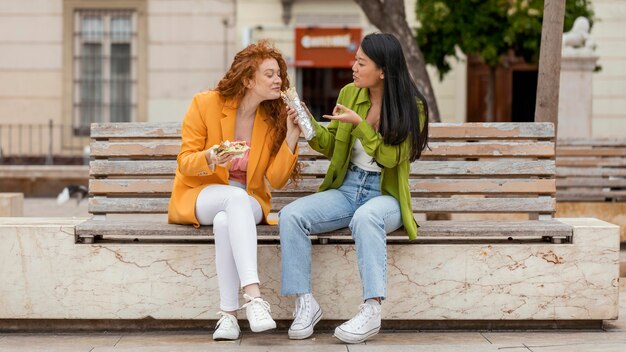 Gelukkige vrouwen die samen straatvoedsel eten