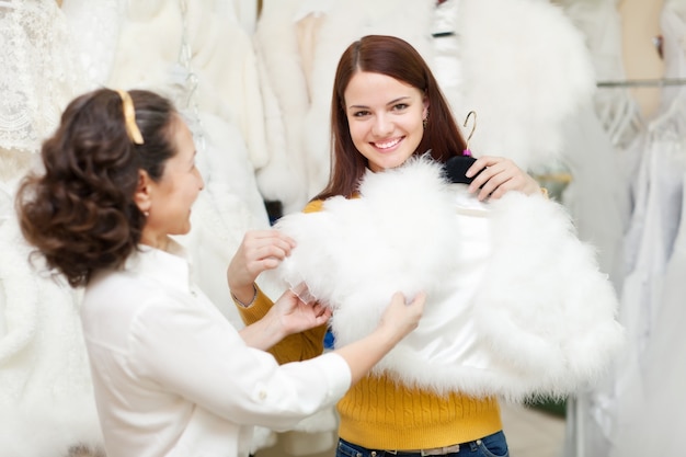 Gelukkige vrouwen kiest vacht cape bij bruiloft winkel