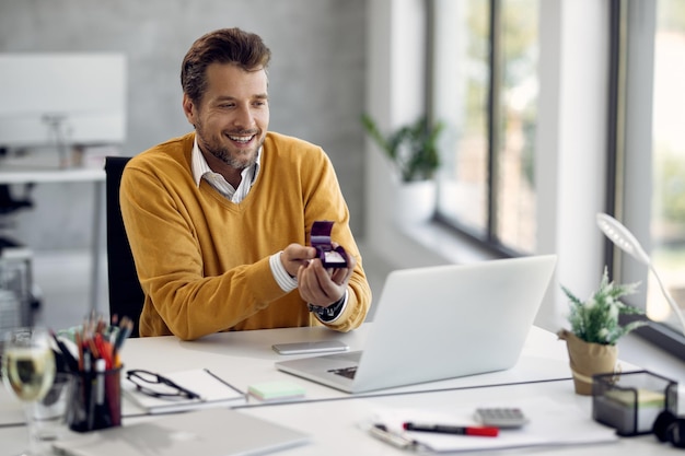 Gratis foto gelukkige zakenman die zijn vriendin voorstelt tijdens een videogesprek via een laptop vanuit zijn kantoor