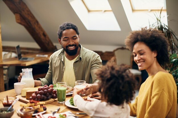 Gelukkige zwarte familie genieten van het ontbijt aan de eettafel thuis