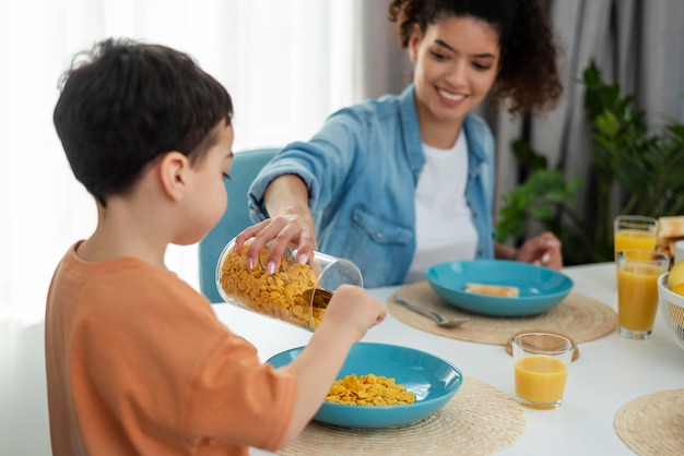 Gelukkige zwarte familie met moeder die jong geitje met cornflakes dient