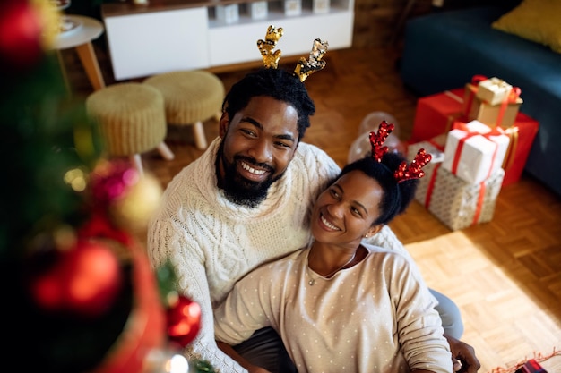 Gelukkige zwarte man en zijn vrouw ontspannen thuis met Kerstmis