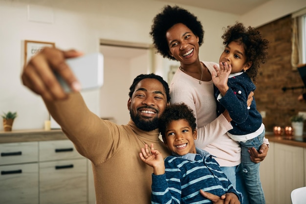 Gelukkige zwarte ouders met kinderen die thuis videobellen via een smartphone