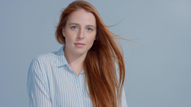 Gratis foto gember hoofd rood haar gember haar model met blauwe grote ogen in studio met naar rechts waaiend haar schoonheid steil glanzend haar waait