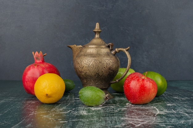 Gemengd vers fruit en klassieke theepot op marmeren tafel.