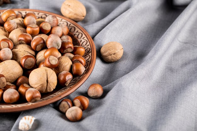 Gemengde noten in een decoratieve aardewerk plaat geïsoleerd op blauwe tafellaken