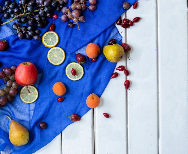 Gemengde vruchten op een blauw lint op een witte tafel.