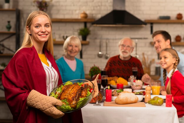 Generaties van het gezin aan de Thanksgiving-tafel en moeder die de kalkoen brengt