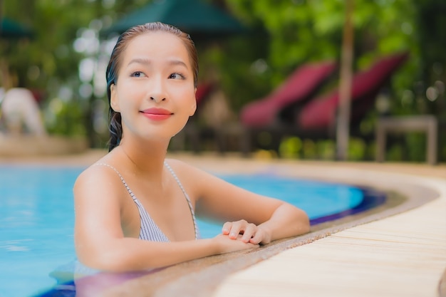 Geniet van ontspannende glimlachvrije tijd van de portret mooie jonge Aziatische vrouw rond openluchtzwembad in hotel