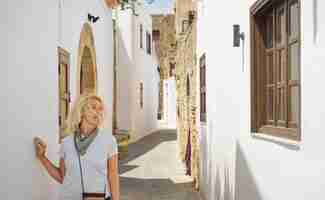 Gratis foto geniet van vakanties in griekenland volwassen reizende vrouw wandelen in de oude griekse stad reizen op de griekse eilanden van de dodekanesos-archipel beroemde vakantie- en reisbestemming