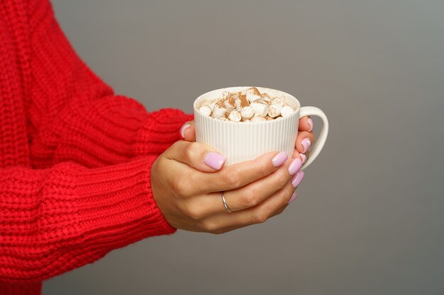Geniet van warme chocolademelk of cacao met marshmallows vrouwelijke houdbeker met verwarmende winter- of herfstdrank