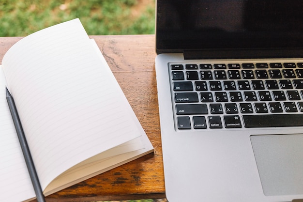 Geopend notitieboekje dichtbij laptop op plank