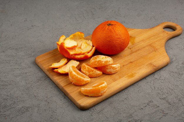 Gepelde mandarijnen samen met hele en gesneden fruit op een bruin bureau