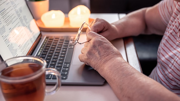 Gepensioneerde vrouw gebruikt laptop handen close-up