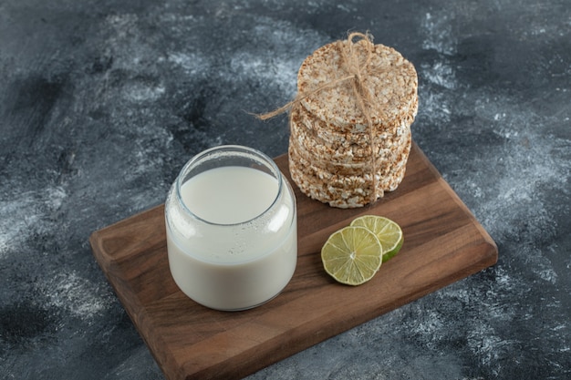 Gratis foto gepofte rijstwafels, schijfje citroen en verse melk op een houten bord