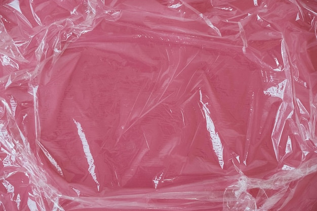 Gerimpelde transparante plastic textuur op een roze achtergrond. transparante cellofaantextuur op een roze achterkant. bovenaanzicht. kopiëren, lege ruimte voor tekst
