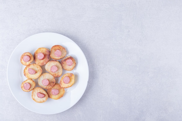 Gerookte worstjes met gebakken aardappel op witte plaat.