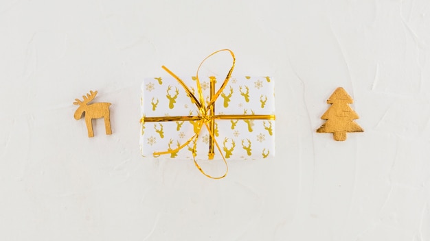 Geschenkdoos in ambachtelijke papier in de buurt van decoratieve herten en dennenboom