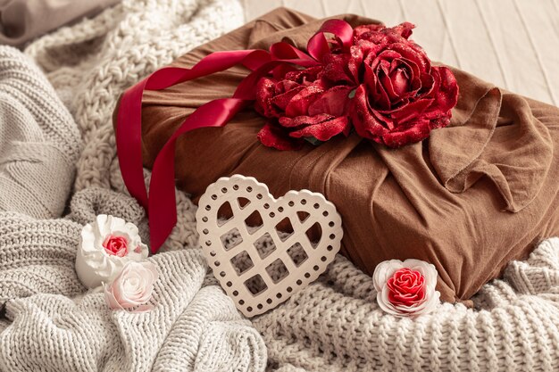 Geschenkdoos versierd met linten en decoratieve rozen op gebreide artikelen. Originele cadeauverpakking voor Valentijnsdag.