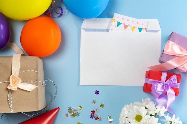 Geschenken in inpakpapier, ballen, pet, bloemen en een envelop met een ansichtkaart op een mooie blauwe achtergrond close-up. uitzicht van boven.