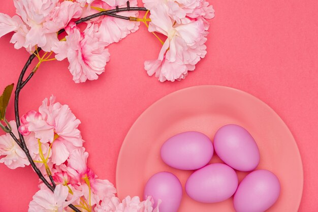 Gratis foto geschilderde eieren op plaat met naast bloem