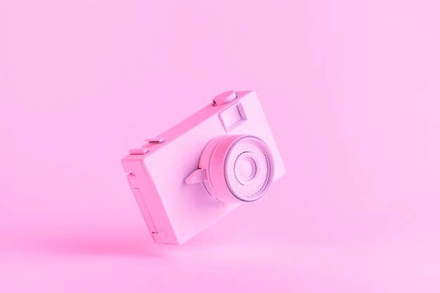 Geschilderde retro camera tegen roze achtergrond