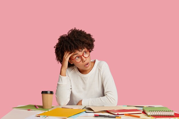 Geschokt Afro-Amerikaanse vrouw draagt een bril, gekleed in witte kleren, werkt aan het opstarten van de schepping,