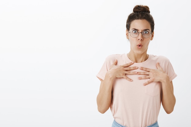 Gratis foto geschokt en beledigd jonge stijlvolle vrouw poseren tegen de witte muur