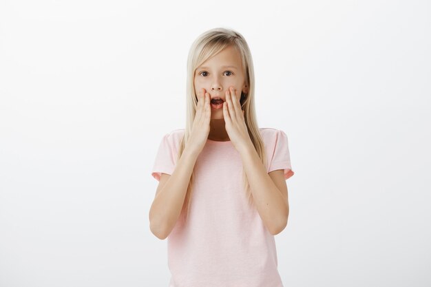 Geschokt en onder de indruk blond meisje hijgend, geamuseerd met open mond