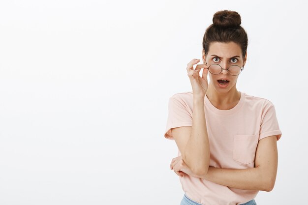 Geschokt hijgend jonge stijlvolle vrouw poseren tegen de witte muur