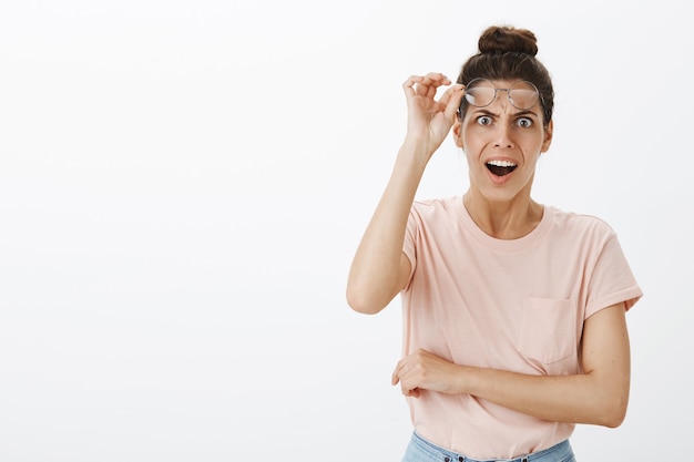 Gratis foto geschokt hijgend jonge stijlvolle vrouw poseren tegen de witte muur