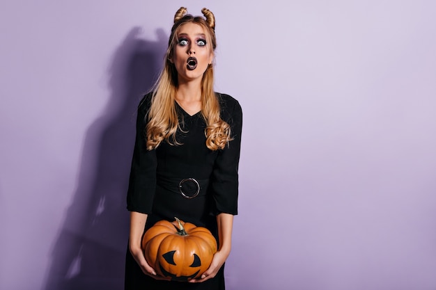 Geschokt langharige vrouw poseren na halloween-maskerade. foto van mooi blond meisje met pompoen.